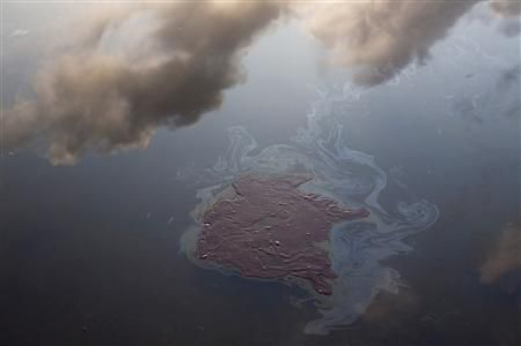 Clouds are reflected in water near a patch of oil from the Deepwater Horizon oil spill off Grand Terre Island, Louisiana