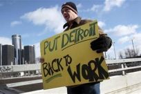 Unemployed worker Pollock carries a sign outside Cobo Center to demonstrate for jobs and good wages before start of press days at North American International Auto show in Detroit, Michigan