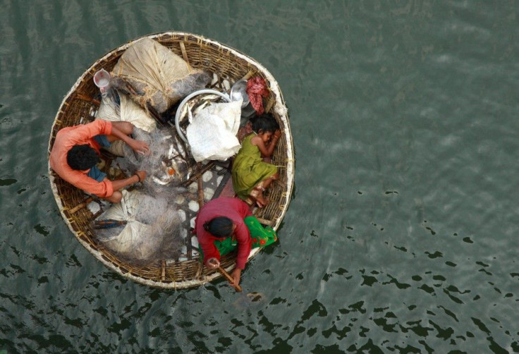 A fisherman arranges a fishing net as his wife paddles their boat in the waters of the Periyar river on outskirts of Kochi