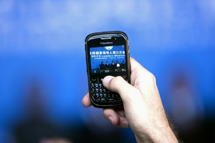 A man uses a Blackberry mobile phone to take a picture of leaders of the BRICS during a joint news conference in Sanya