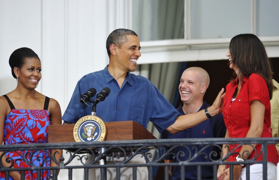 Obama and his wife Michelle smile with U.S. servicemen as he addresses an Independence Day barbeque at the White House in Washington