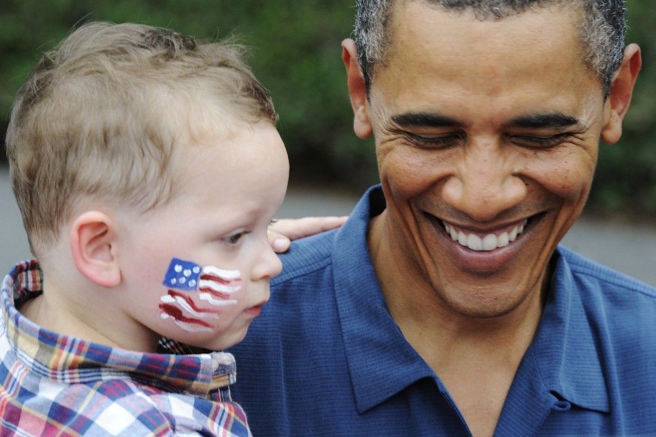 Obama holds a toddler at an Independence Day barbeque for members of the military at the White House in Washington
