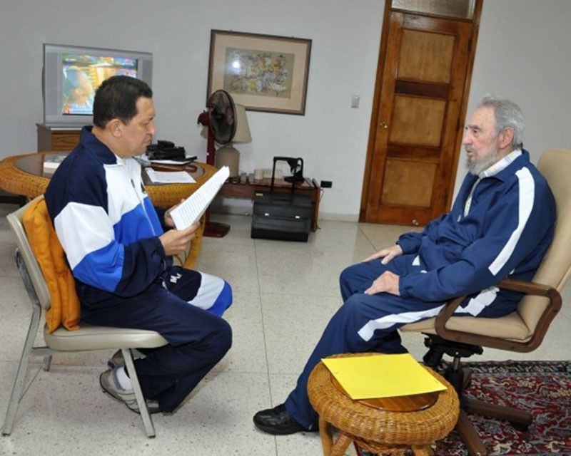 Cuban leader Fidel Castro looking on as Venezuelas President Hugo Chavez reads a document