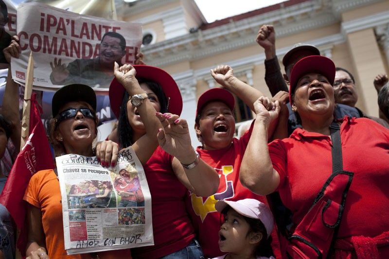 Supporters of Venezuelan President Hugo Chavez hold newspapers with a picture of him