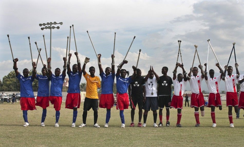 Haitian soccer players of the Zaryen team blue and the national amputee team white greet the crowd before a friendly match in Port-au-Prince