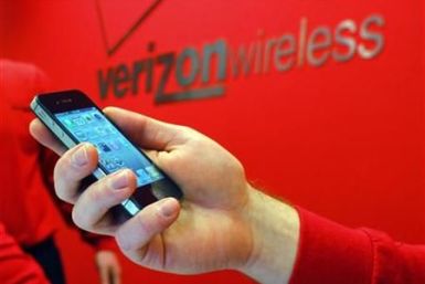 Employee holds out an iPhone for a customer at a Verizon store in Boston