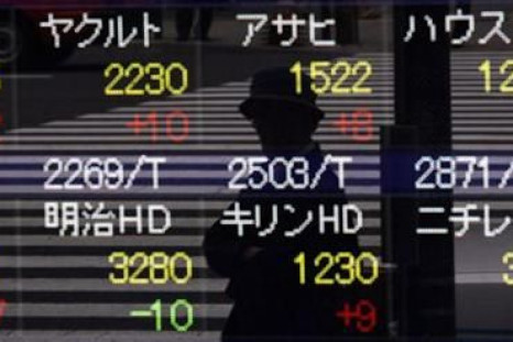 A pedestrian is reflected in a stock index board outside a brokerage house in Tokyo