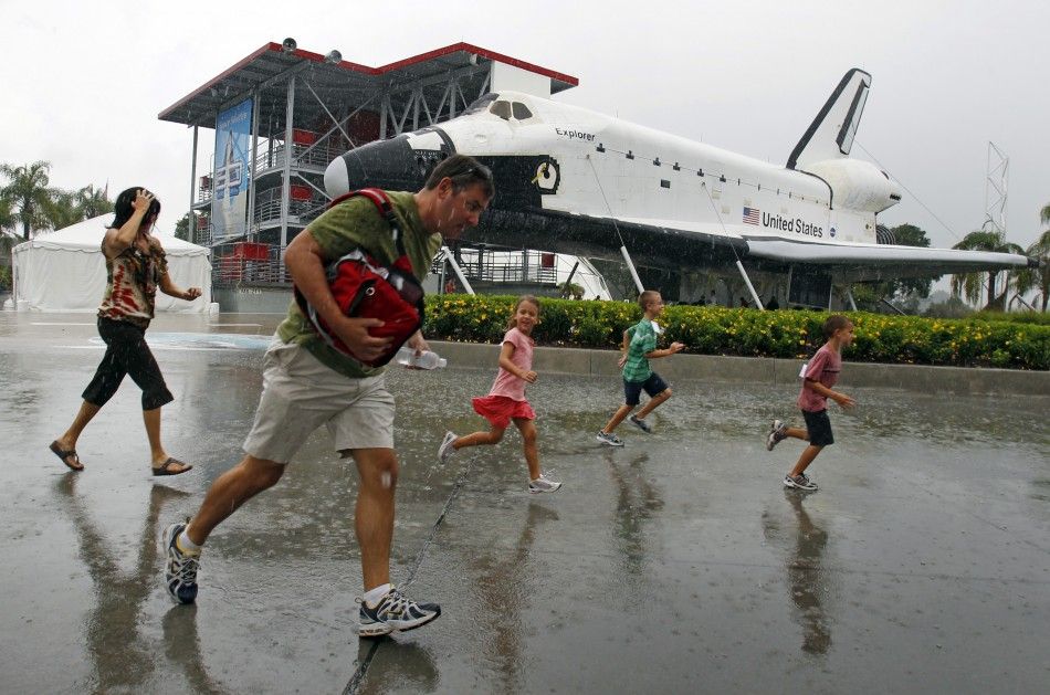Visitors run for cover from the rain at the Kennedy Space Visitor Center Complex near Cape Canaveral
