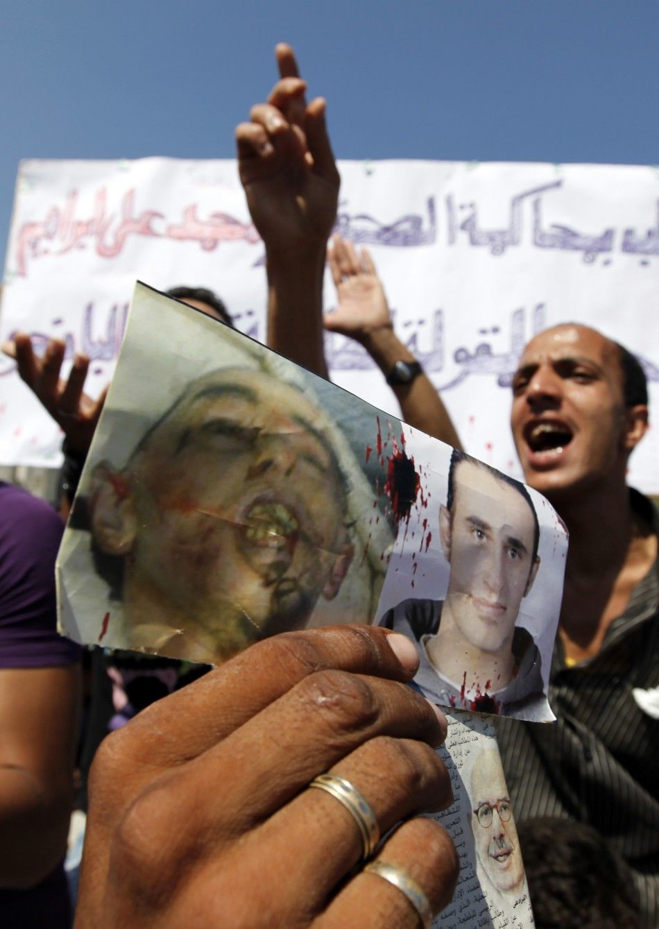 Demonstraters carry pictures of activist Said and chant anti-police slogans outside court building during trial of two p