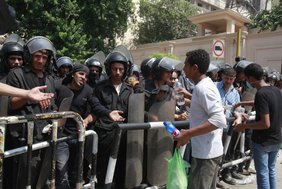 Protesters give vinegar to riot police members in front of the Interior Ministry after clashing with riot police with st...