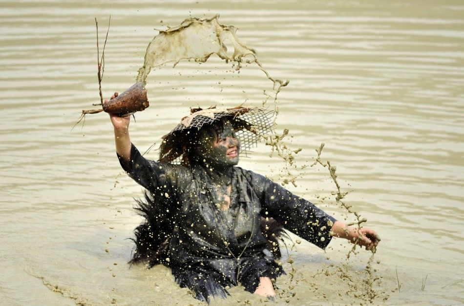 A woman splashes water with a container as she performs the Shuigu dance during a cultural festival in Jianhe county, Guizhou province July 6, 2011. The dance, which is also known as the water drum dance, has a history of over 500 years in local Miao vill