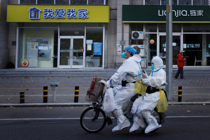 Pandemic prevention workers in protective suits ride an electric bike as outbreaks of coronavirus disease (COVID-19) continue in Beijing