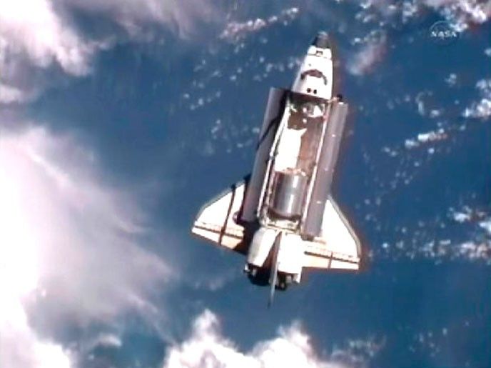 The space shuttle Atlantis is seen with earth in the background as it draws near the International Space Station for docking