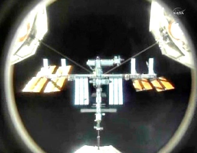 The International Space Station is seen in the crosshairs of the mating adapter mounted in the space shuttle Atlantis payload bay