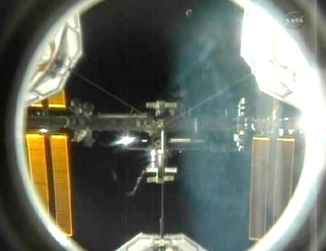 The International Space Station is seen in the crosshairs of the pressurized mating adapter mounted in the space shuttle Atlantis payload bay