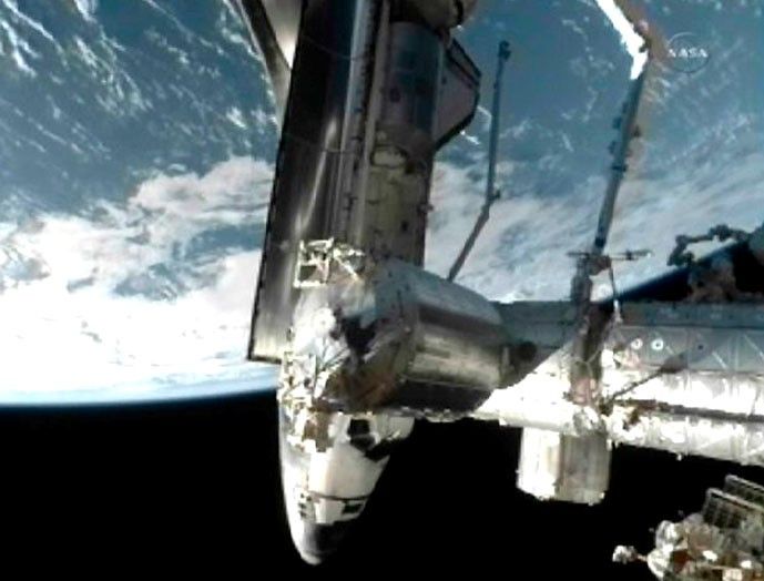 The space shuttle Atlantis is seen docked to the International Space Station with the earth in the background