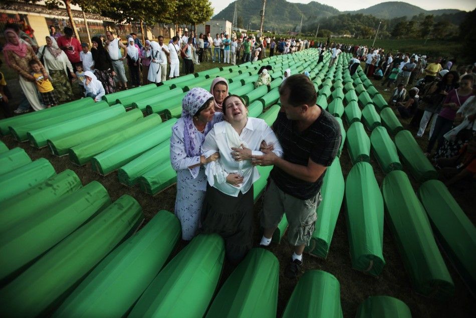 Bosnian Muslims cry near coffins prepared for a mass burial at the Memorial Center in Potocari, near Srebenica