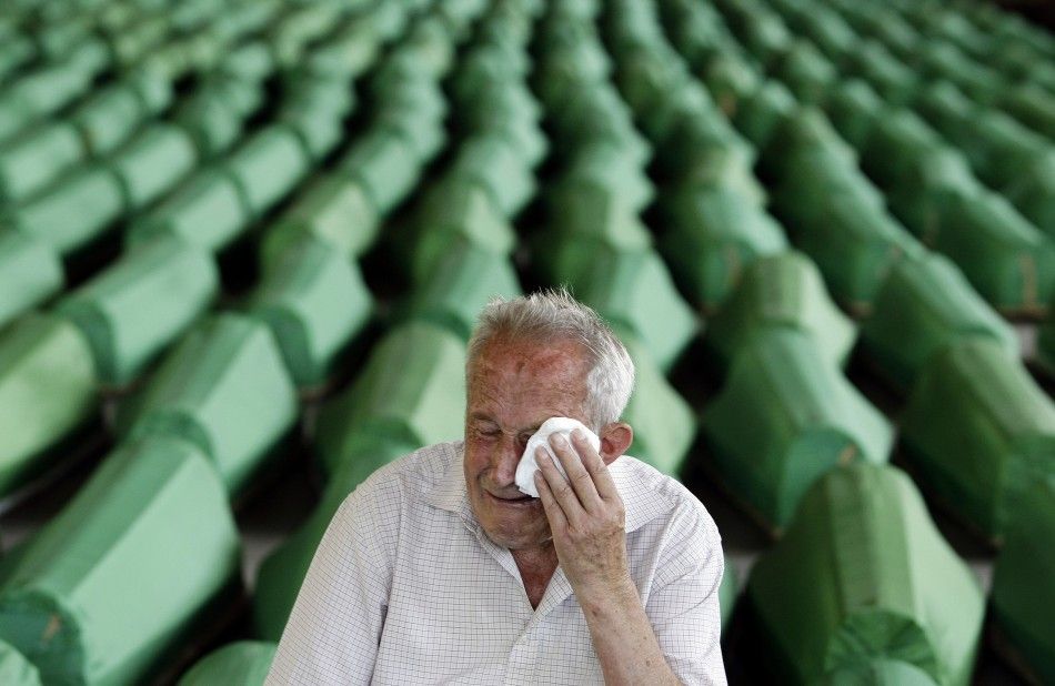 A man mourns in front of coffins prepared for a mass burial at the Memorial Center in Potocari, near Srebenica
