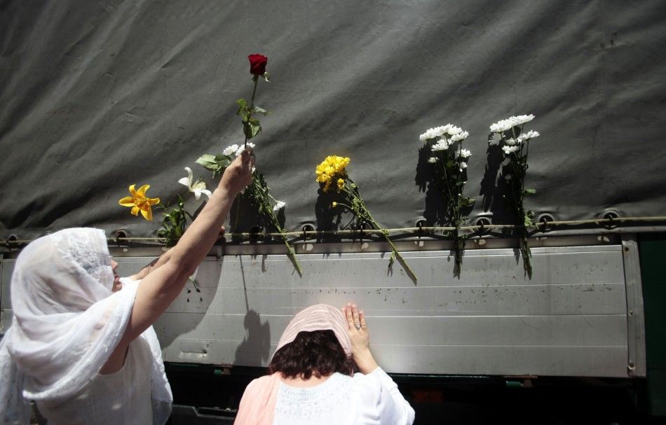 Bosnian women put flowers on one of the trucks carying 614 coffins of newly identified victims of the 1995 Srebrenica massacre in front of the presidential building in Sarajevo