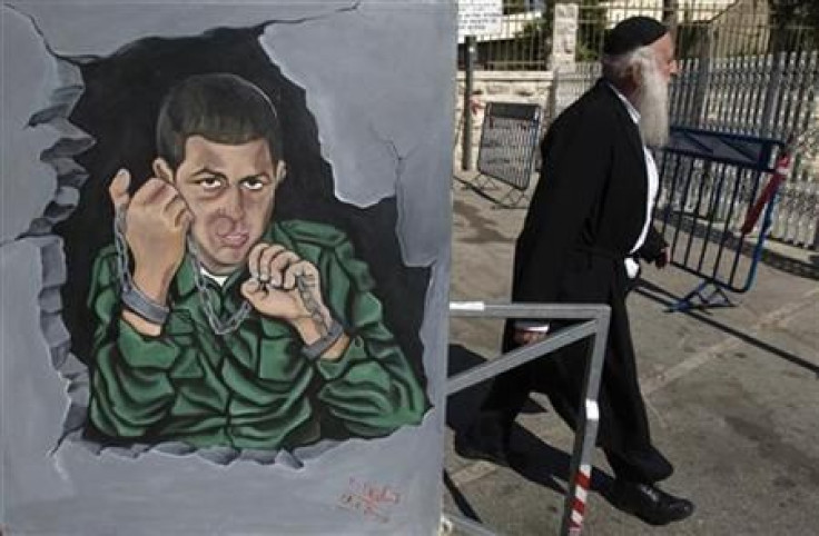 Pedestrian walks past a painting, depicting Israeli soldier Shalit, hung outside a protest tent in Jerusalem