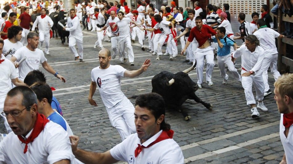 Victoriano del Rio fighting bull falls next to runners at Estafeta corner during the sixth running of the bulls at the San Fermin festival in Pamplona.