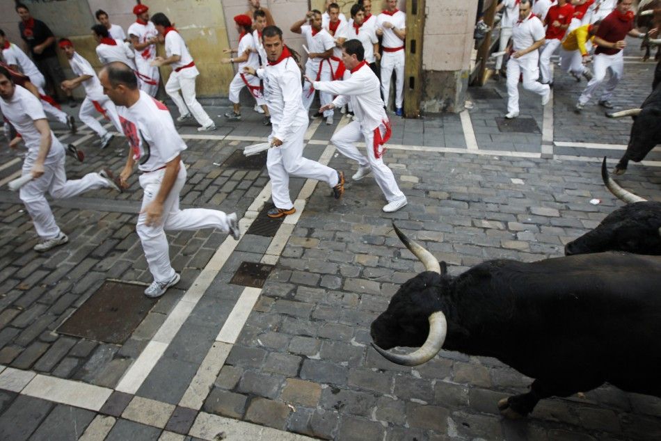 Runners sprint ahead of Victoriano del Rio fighting bulls at Estafeta corner during the sixth running of the bulls at the San Fermin festival in Pamplona