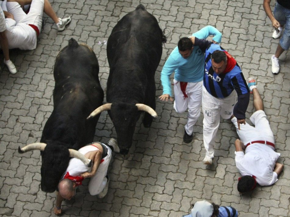 A runner falls in the way of two Victoriano del Rio fighting bulls at the entrance to the bullring during the sixth running of the bulls at the San Fermin festival in Pamplona