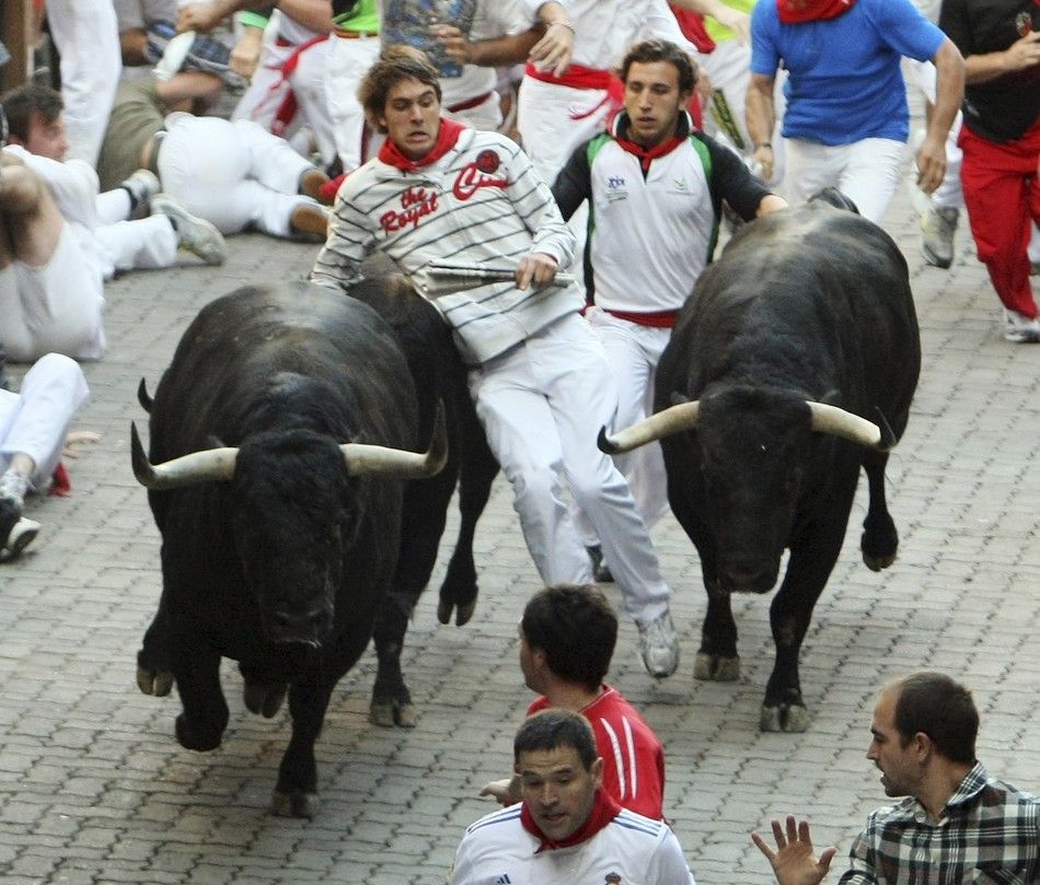 A runner is caught in between two Victoriano del Rio fighting bulls at the entrance to the bullring during the sixth running of the bulls at the San Fermin festival in Pamplona