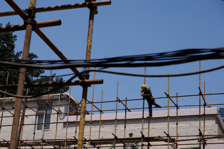 A worker tightens a scaffolding joint at a construction site of an apartment building under refurbishment in Beijing