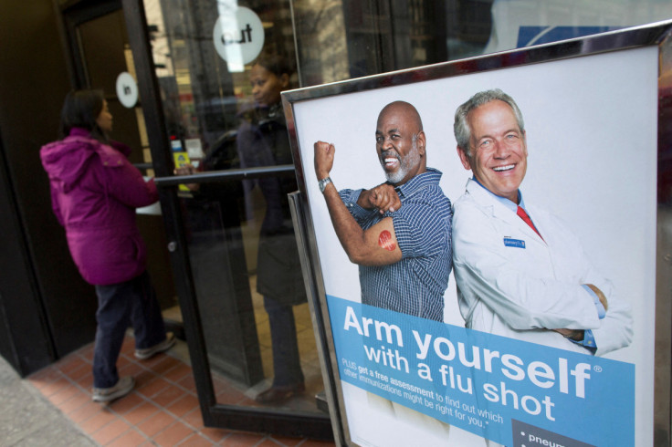 People enter a pharmacy next to a sign promoting flu shots in New York