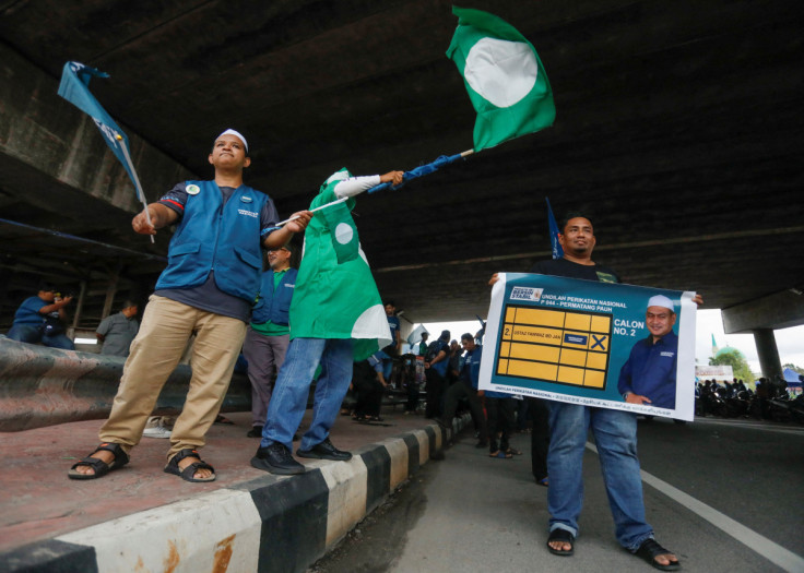 Pan-Malaysian Islamic Party (PAS) supporter waves the party's flag as they campaign for the party's candidate who is contesting in Malaysia's general election under the political coalition of Perikatan Nasional at Permatang Pauh