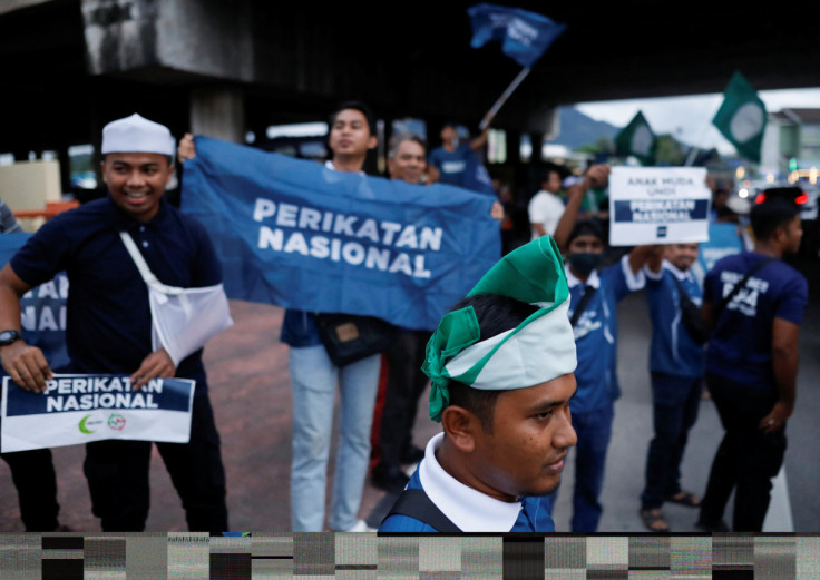 A Pan-Malaysian Islamic Party (PAS) supporter wraps his head with the party's flag as he campaigns for PAS' political coalition, Perikatan Nasional during the campaign period of Malaysia's general election at Permatang Pauh