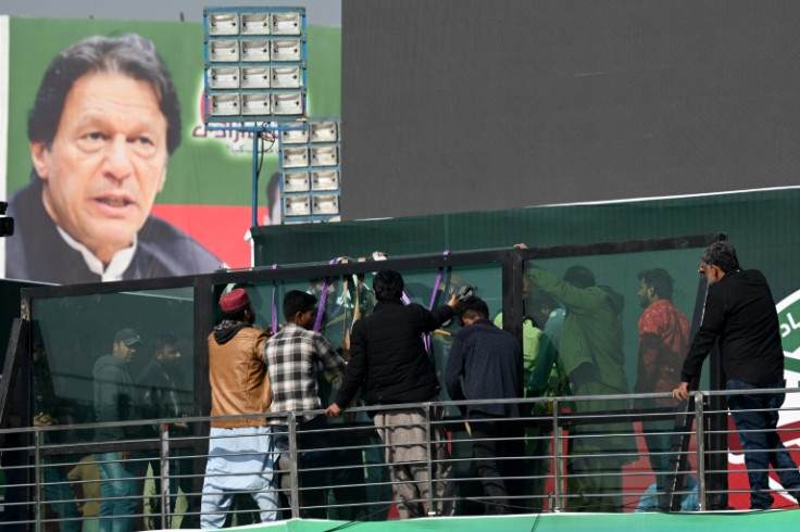Workers install a bullet proof glass shield on the main stage where former prime minister Imran Khan was to speak