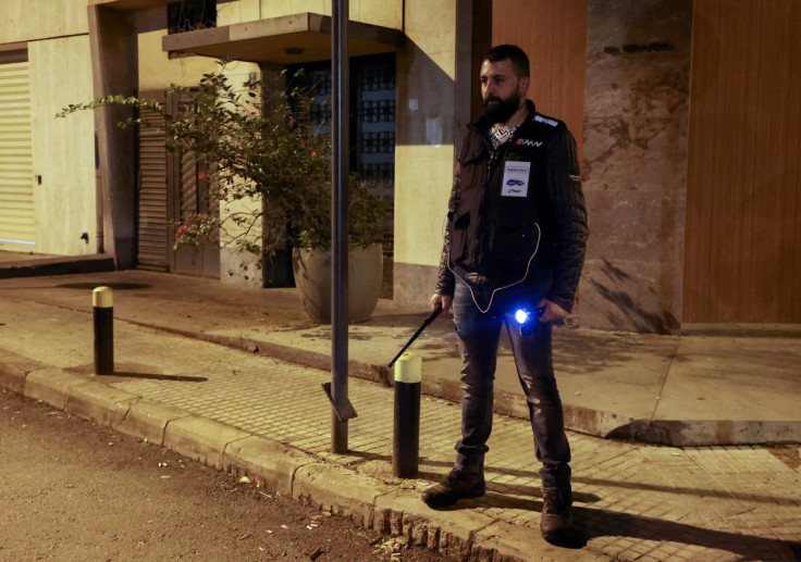 A member of 'neighborhood watch' carries a baton and a torch light as he stands guard, in Ashrafieh