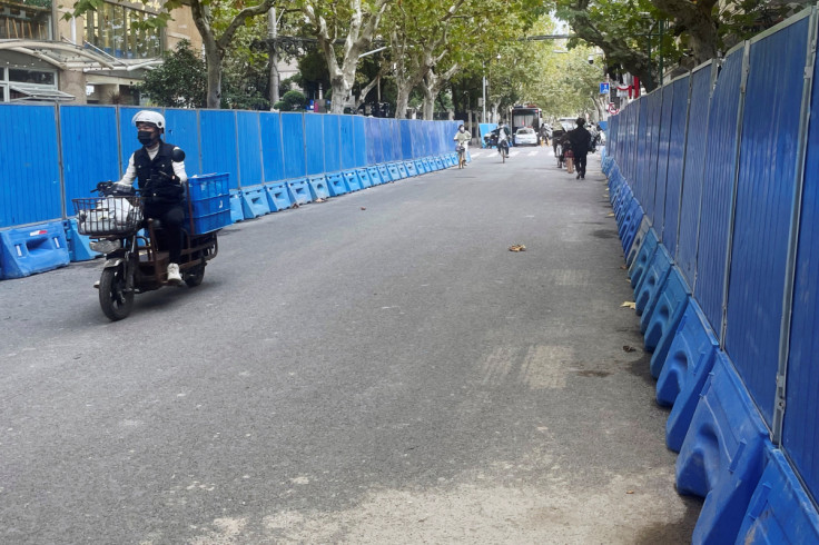 People ride past barriers set up along a road in Shanghai