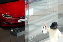 A woman walks past a Tesla dealership in Hanam