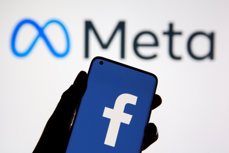 A smartphone with Facebook's logo is seen in front of displayed Facebook's new rebrand logo Meta in this illustration