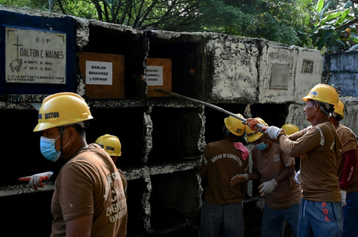 A prison inmate pushes a coffin into a tomb during a mass burial of 70 unclaimed bodies of prisoners at New Bilibid Prison Cemetery in Muntinlupa, Manila