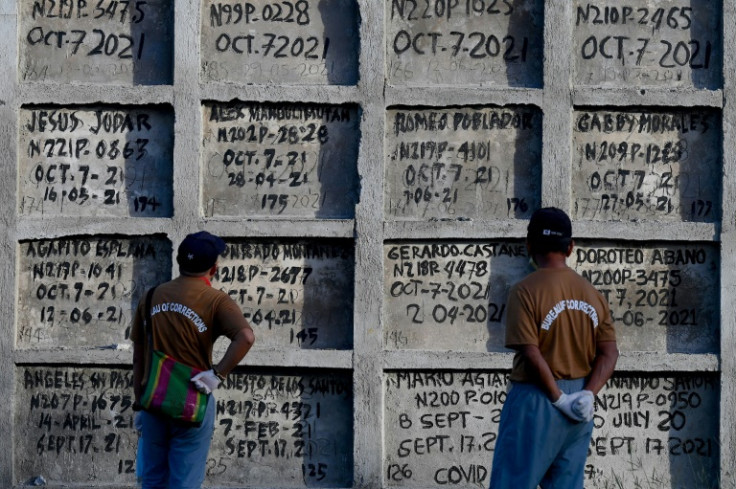 Inmates look at tombs during the mass burial of 70 unclaimed bodies at New Bilibid Prison Cemetery in Manila