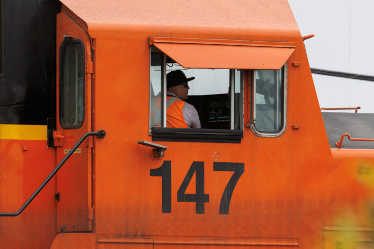 Railway workers load railcars onto train in California