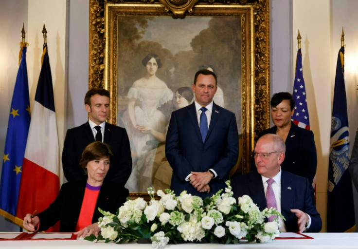 French President Emmanuel Macron (standing left) looks on as French Foreign Minister Catherine Colonna and Louisiana Governor John Bel Edwards (bottom right) sign a clean energy accord in New Orleans on December 2, 2022