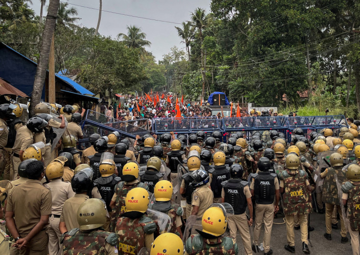 Police officers stand guard near the barricades during a protest rally by the supporters of the proposed Vizhinjam port project