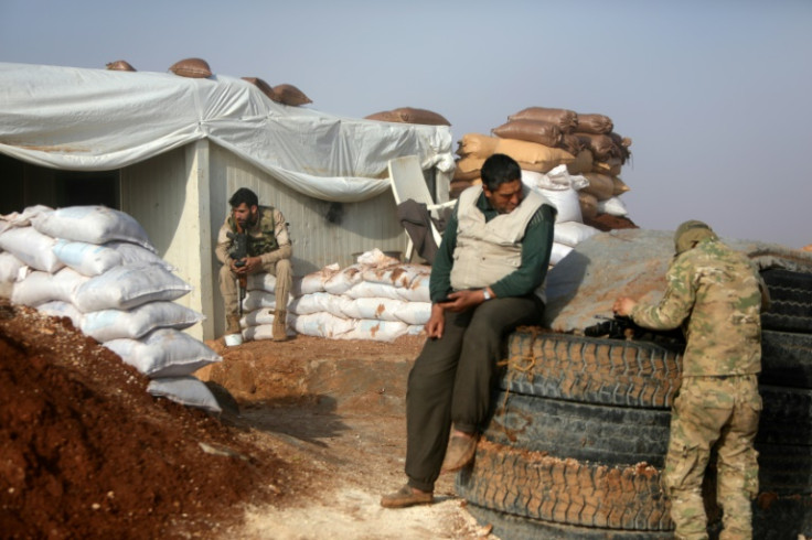 Turkish-backed Syrian fighters kill time at a position on the front line with Kurdish forces in Tal Rifaat