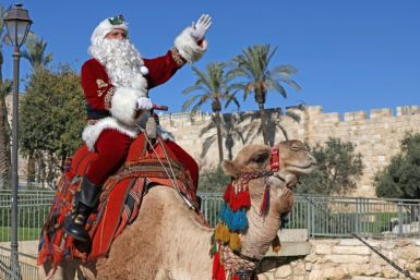 Issa Kassissieh, dressed as Santa Claus, poses for a picture as he rides a camel at Jaffa Gate in Jerusalem's Old City