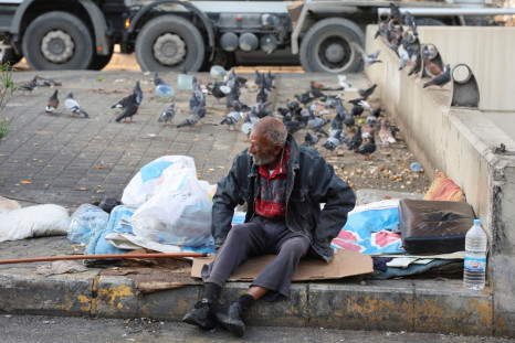 A homeless man sits on a curb along a street, in Beirut