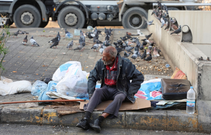 A homeless man sits on a curb along a street, in Beirut