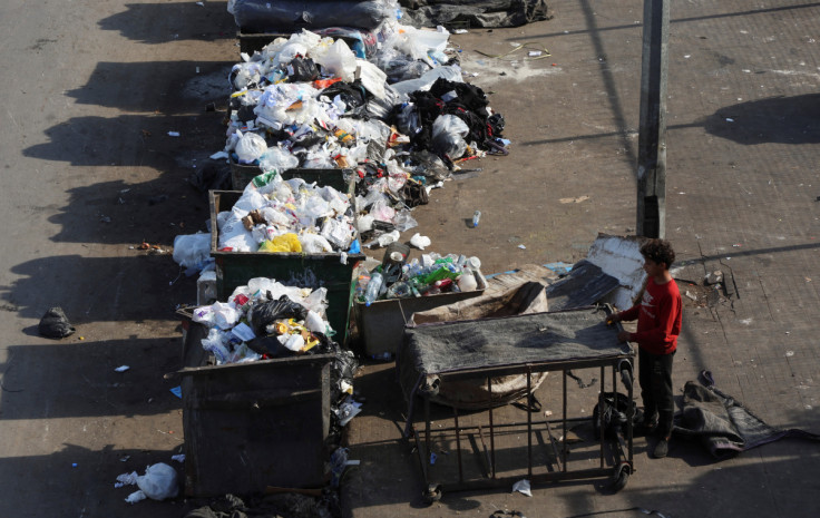 A boy stands near a dumpster, in Beirut