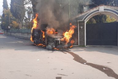 A police vehicle burns as people take part in a protest, in Sweida