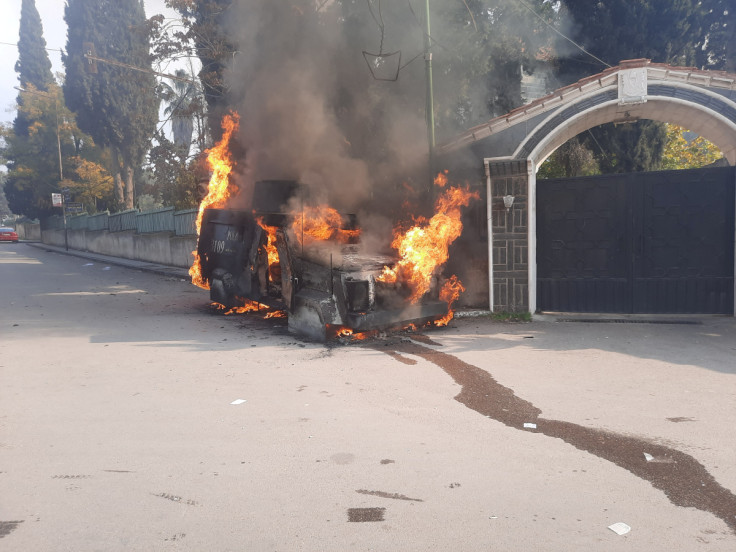 A police vehicle burns as people take part in a protest, in Sweida