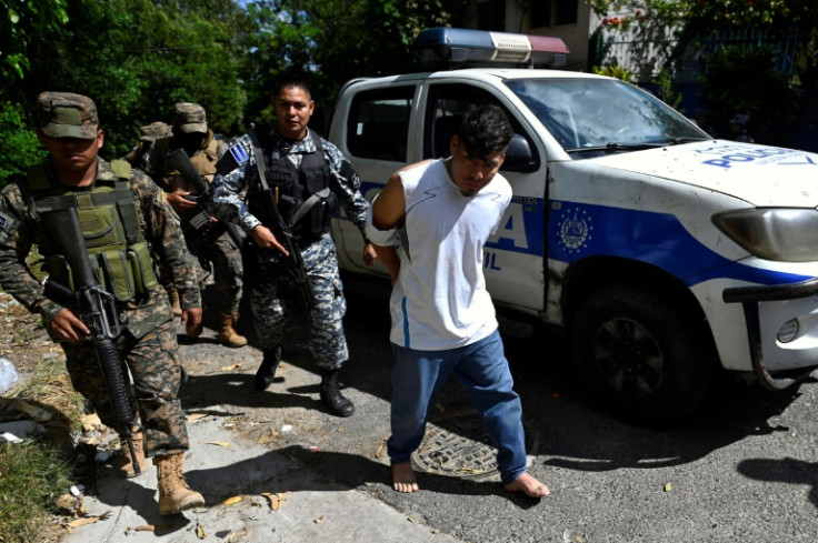 Police and soldiers escort a detainee during the anti-gang raid in Soyapango